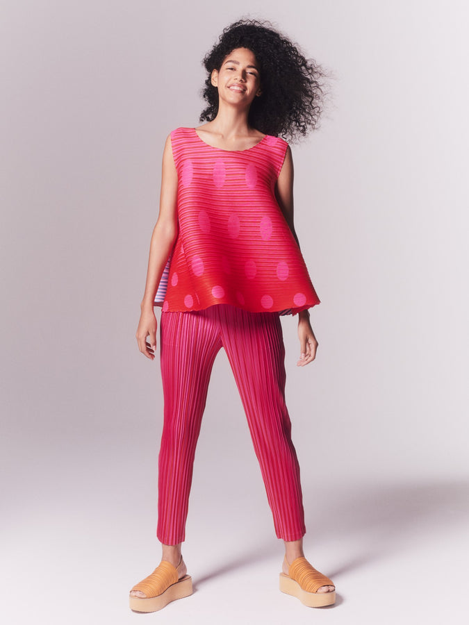 Model wearing VEGE MIX 1 top and trousers in pink and red. Paired with orange platform sandals.