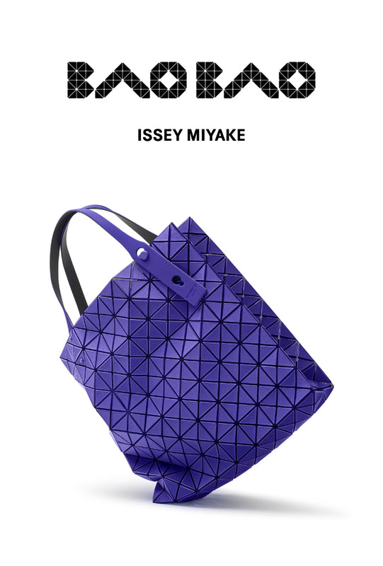 White background. Top: BAO BAO ISSEY MIYAKE logo in black. Bottom: PRISM PLUS tote bag in blue standing on one corner, tilted.
