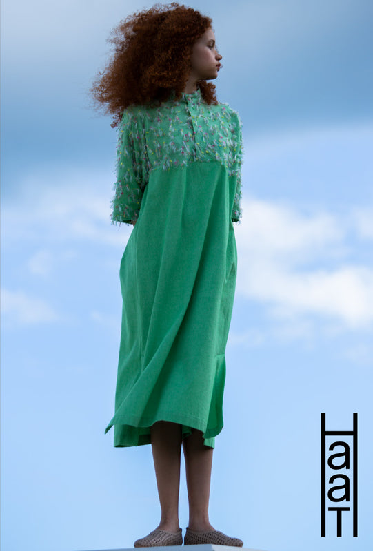 Three sections. Left: Model wearing HOPPING COTTON short-sleeved midi dress in green standing with arms behind back and looking to the left. Background of blue sky with clouds. Paired with beige mesh sandals. HaaT logo in black in bottom right corner. 