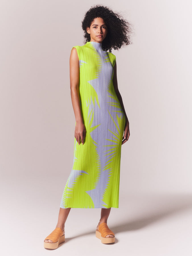 Model wearing PIQUANT dress in yellow green and purple print and platform sandals.