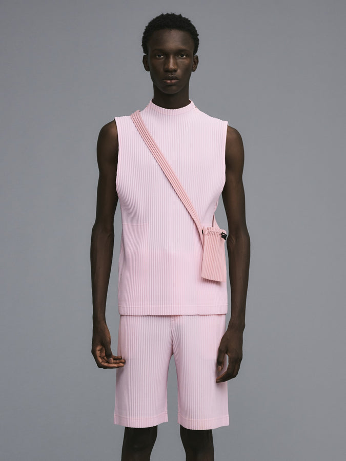 Model wearing pink top and shorts and a pink bag. Grey background.