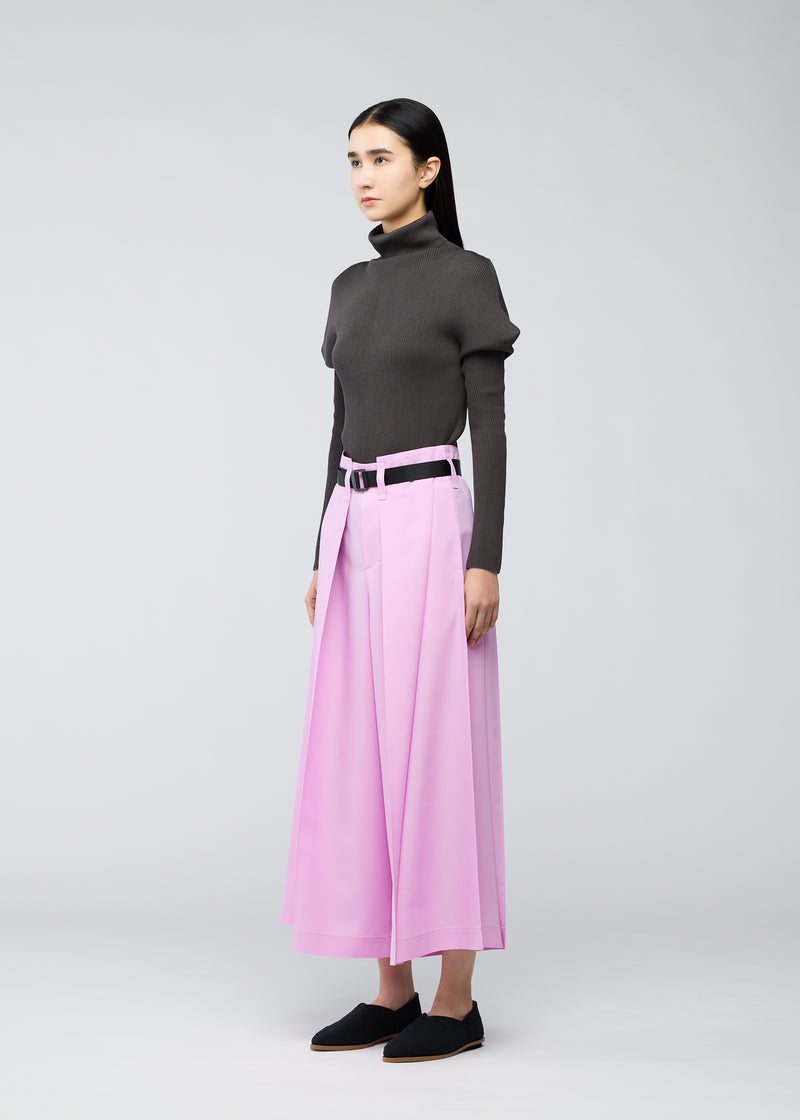 A model wears the 132 5. ISSEY MIYAKE  OBLIQUE FOLD BOTTOMS trousers