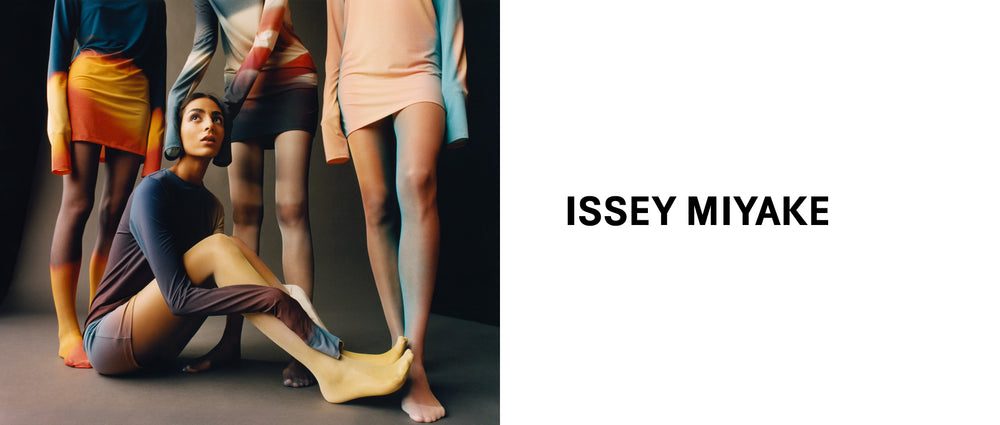 Left: 4 models posing in LIGHT LEAK tunics and tights, all in different print colourways. 3 standing and one sitting on the floor with their arms around their knees. Right: ISSEY MIYAKE logo in black on white background.