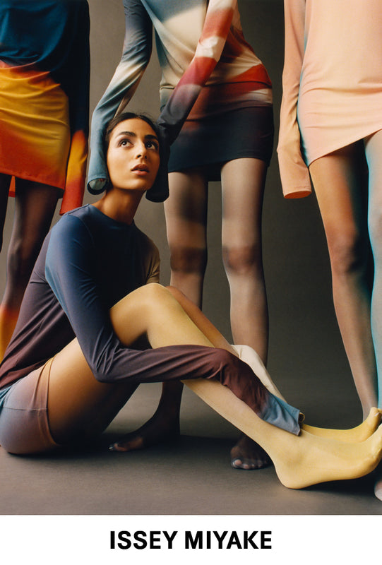 Top: 4 models posing in LIGHT LEAK tunics and tights, all in different print colourways. 3 standing and one sitting on the floor with their arms around their knees. Bottom: ISSEY MIYAKE logo in black on white background.